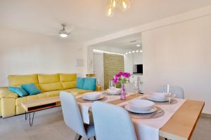 a dining room with a table and a yellow couch at SunShine Vista al Compás in Córdoba