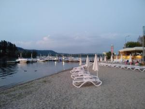 eine Reihe von weißen Stühlen und Sonnenschirmen am Strand in der Unterkunft Appartamento sul lago Maggiore in Castelletto sopra Ticino