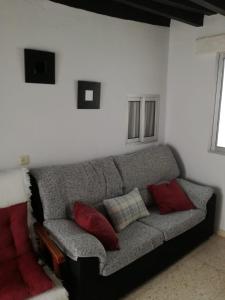 sala de estar con sofá gris y almohadas rojas en Casa López, en Vejer de la Frontera