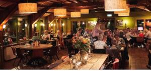 a crowd of people sitting at tables in a restaurant at Luxe chalet Beekbergen nl in Beekbergen