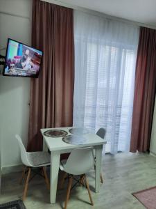 un tavolo bianco con sedie in una camera con TV di Apartman Casa Lux a Vrnjačka Banja