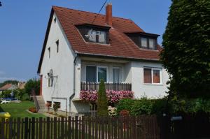 a white house with a red roof and a fence at Karolina Appartman in Balatonkeresztúr