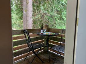 a table and chairs on a porch with a glass of wine at Mountain Meadows Inn & Chalet Suites in Ashford