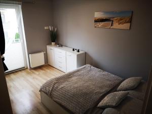 a bedroom with a bed and a dresser and a window at Apartament Edyta in Świnoujście