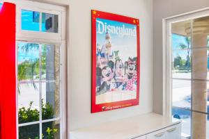 a poster of disneyland on a wall in a room with windows at Hotel 414 Anaheim in Anaheim