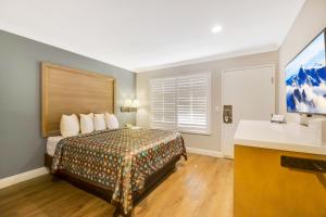 a hotel room with a bed and a flat screen tv at Hotel 414 Anaheim in Anaheim