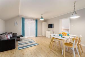 a living room with a table and chairs in a room at Plażowe Apartamenty Grzybowo in Grzybowo
