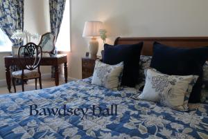 a bedroom with a blue bed with pillows and a desk at Bawdsey Hall in Bawdsey