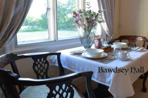 a dining room table with a vase of flowers on it at Bawdsey Hall in Bawdsey