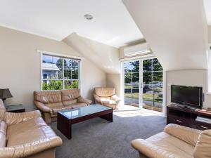 a living room with couches and a flat screen tv at Elizas Townhouse in Port Fairy