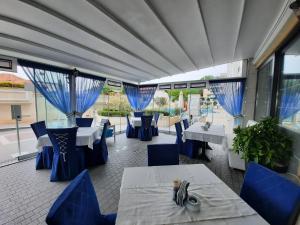 a restaurant with blue chairs and tables and windows at Private Super apartments by sea in Apart Hotel ! in Pomorie