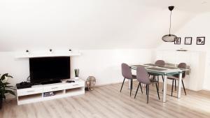 a white living room with a table and a tv at Sam's Place in Kreuzwertheim