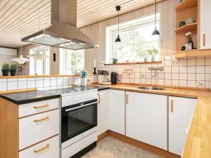 una cucina con armadi bianchi e piano cottura di 8 person holiday home in Bl vand a Blåvand