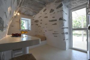 a room with a stone wall and a window at The stone in Tinos