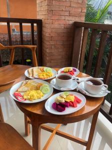 a wooden table with plates of breakfast food on it at The Kertha Ubud in Ubud