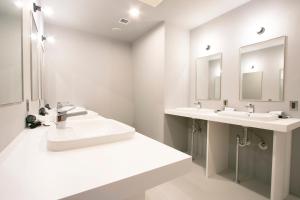 een witte badkamer met 2 wastafels en 2 spiegels bij Theatel Sapporo in Sapporo
