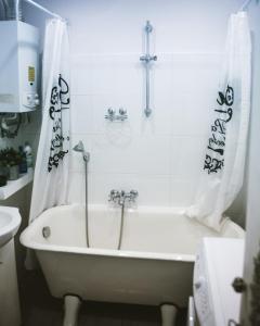 a white bath tub in a bathroom with a sink at Modern retro apartament Katowice in Katowice