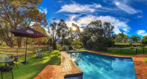 a swimming pool with a table and an umbrella at Mountain View Motor Inn & Holiday Lodges in Halls Gap