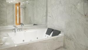 een badkamer met een wit bad en een spiegel bij Glarun Jinling Hotel in Nanjing