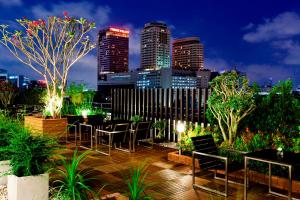 un toit-terrasse avec des tables et des chaises et une vue sur la ville. dans l'établissement Royal Princess Larn Luang - SHA Extra Plus, à Bangkok