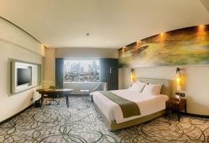 um quarto de hotel com uma cama grande e uma janela em Grand Mercure Medan Angkasa em Medan