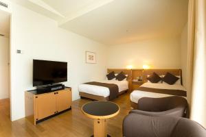 a hotel room with two beds and a flat screen tv at Hotel Nagoya Garden Palace in Nagoya