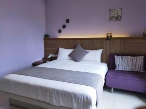 een slaapkamer met een groot bed en een paarse bank bij Mysig in Luodong