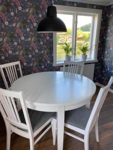 une table à manger blanche avec des chaises et une lampe pendant dans l'établissement Yxefall Norrgården, à Kisa