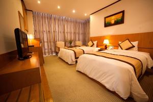 a hotel room with two beds and a flat screen tv at Danang Petro Hotel in Da Nang