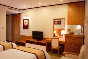 a hotel room with two beds and a desk with a television at Danang Petro Hotel in Da Nang