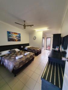 a hotel room with two beds and a television at Sunseeker Motel in Hervey Bay