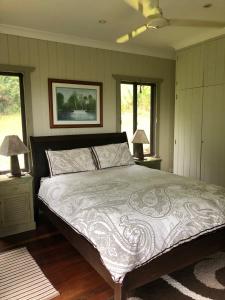 a bedroom with a large bed with two windows at daintree valley cottage in Daintree