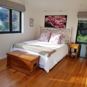 a bedroom with a white bed and a wooden floor at The Rectangle Apartment, Akaroa in Akaroa
