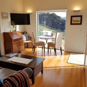 sala de estar con mesa, sillas y TV en The Rectangle Apartment, Akaroa, en Akaroa