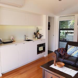 una cucina con armadi bianchi e un soggiorno con divano. di The Rectangle Apartment, Akaroa ad Akaroa