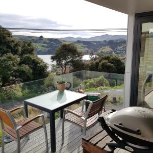 una mesa y sillas en un balcón con vistas en The Rectangle Apartment, Akaroa, en Akaroa