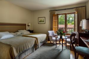 Habitación de hotel con 2 camas, mesa y ventana en Parador de Gijón, en Gijón