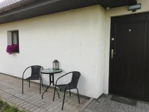 a patio with two chairs and a table and a door at Leśny Apartament II in Szczytno