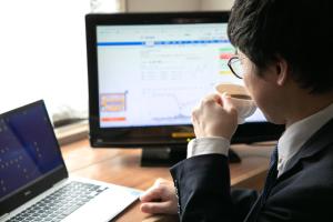 a man sitting at a desk using a laptop computer at Hotel New Green in Nagaoka