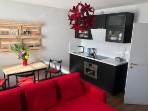 a living room with a red couch and a kitchen at Ferienwohnungostseeblick in Börgerende-Rethwisch