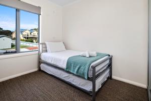 Un dormitorio pequeño con una cama y una ventana. en GRANITE BEACH HOUSE @ Bay of Fires, en Binalong Bay