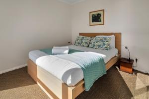 una camera da letto con un grande letto con lenzuola bianche e cuscini blu di GRANITE BEACH HOUSE @ Bay of Fires a Binalong Bay