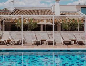 勒格罗-迪鲁瓦Oustau Camarguen Hôtel & Spa的游泳池旁设有躺椅和桌子