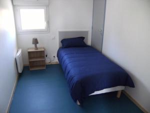 - une chambre avec un lit bleu et une fenêtre dans l'établissement Les Sables d'or, à Agon-Coutainville