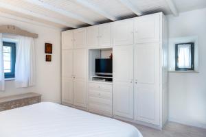 a white bedroom with a bed and a tv at Authentic Cretan Stone Windmill in Sitia