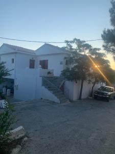 una casa blanca con un coche aparcado delante de ella en ΑΡΜΟΝΙΑ ΣΤΟΥΝΤΙΟ en Gialiskari