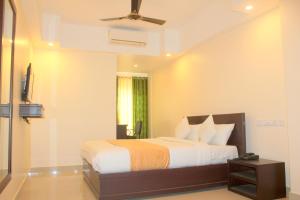 um quarto com uma cama e uma ventoinha de tecto em Aura Residency em Thrissur