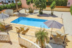 een zwembad met stoelen en parasols naast bij Villa Coral Bee - walking distance to Coral Bay Beach in Peyia