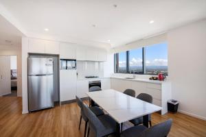 a kitchen with a table and chairs and a refrigerator at Ruby Gold Coast in Gold Coast