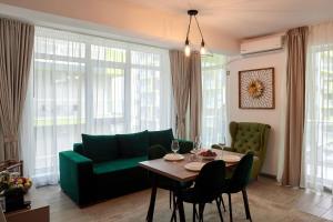 uma sala de estar com um sofá verde e uma mesa em Sea la Vie 2BR Apt Spa n Pool Beach resort em Mamaia Nord – Năvodari